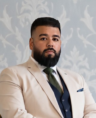Joshua Pal wearing a cream jacket, navy waistcoat and green tie